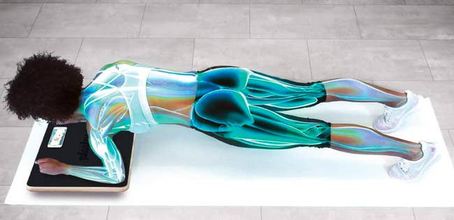 Model in plank position while placing wrists and elbows on a gold interactive Plankboard