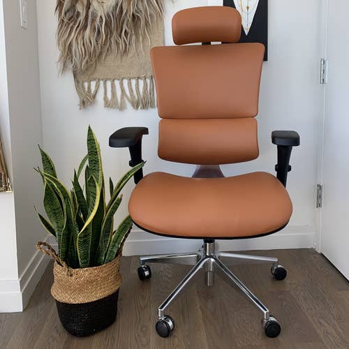 Leather office chair on wheels with padded seat, headrest, arm rests, and rounded lumbar support 