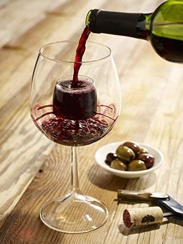 wine glass with wine being poured into the inner cup with holes for aerating