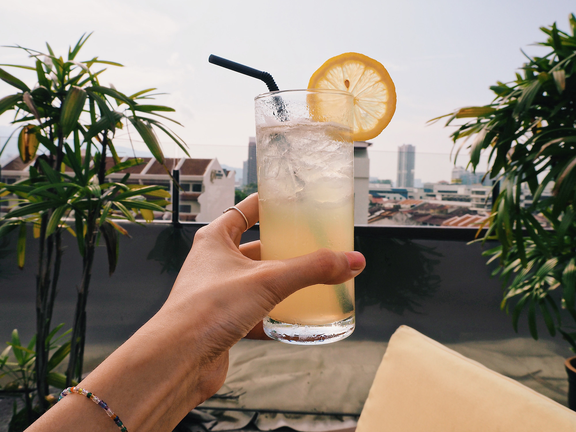 A woman&#x27;s hand holding a cocktail up outside. 