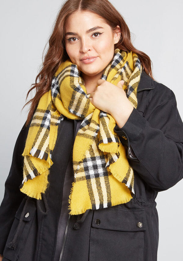 A person wearing a patterned blanket scarf around their neck