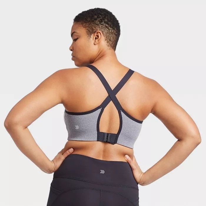 Model wears gray and black sports bra with criss crosses on the back and black leggings