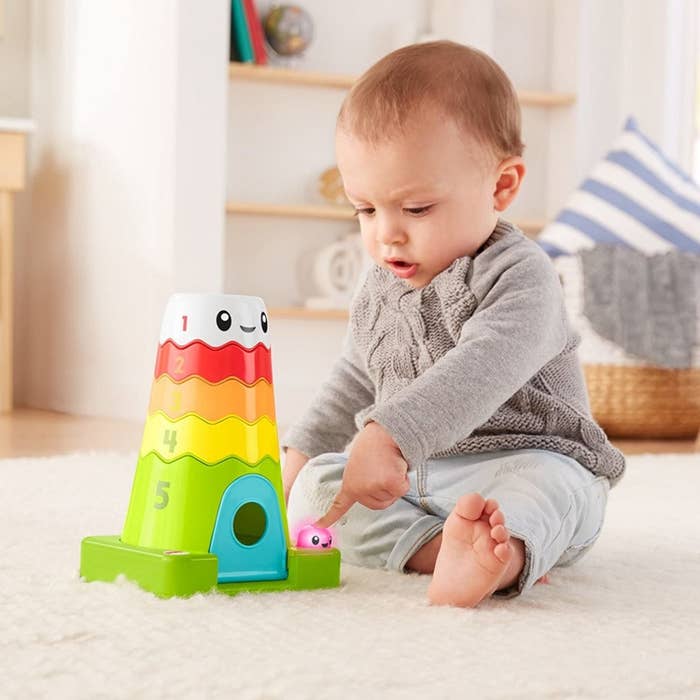 Baby model playing with colorful stackable mountain and plastic bear toy