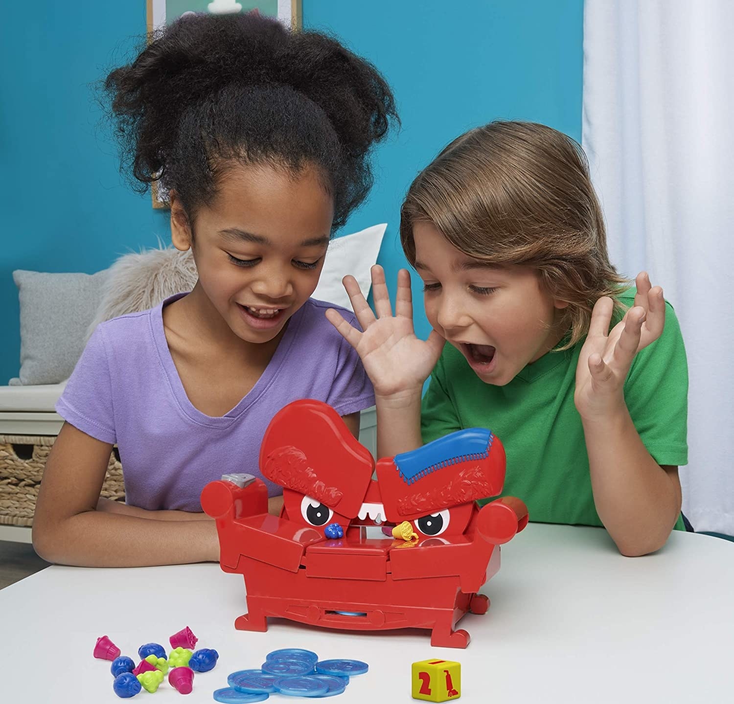 Two child models playing with red plastic couch game
