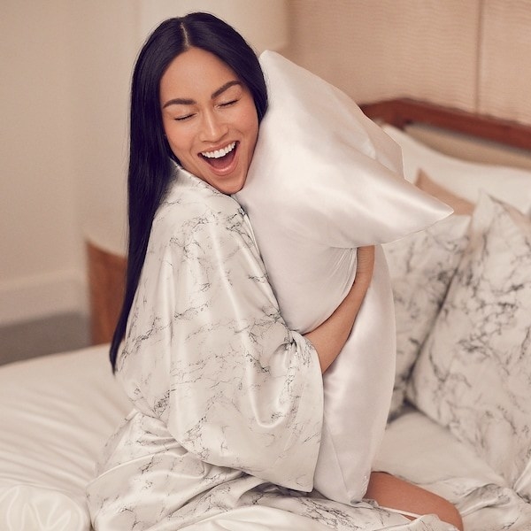 model hugging a pillow with the Slip silk pillowcase in white 