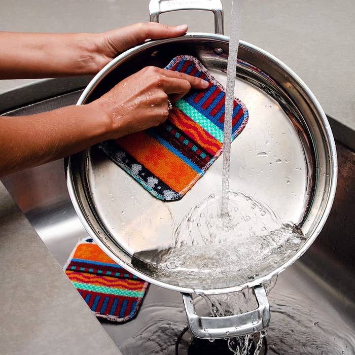A person scrubbing a pan with a scrubber