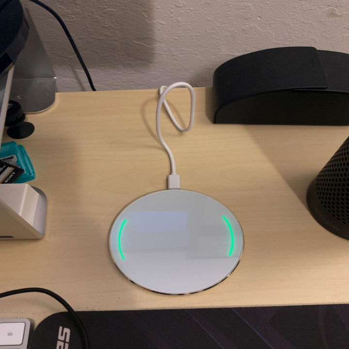 reviewer photo showing white mirror charging pad on a nightstand