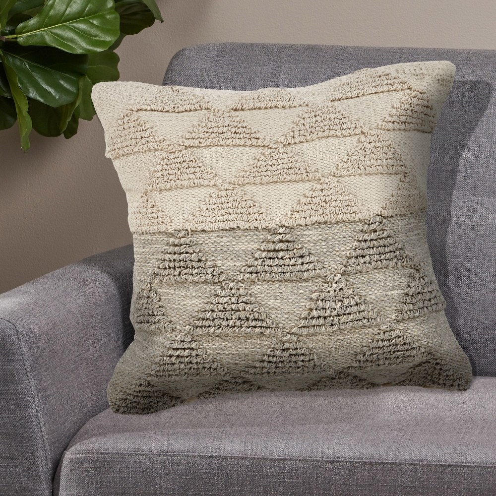 A neutral triangle patterned pillow on a couch