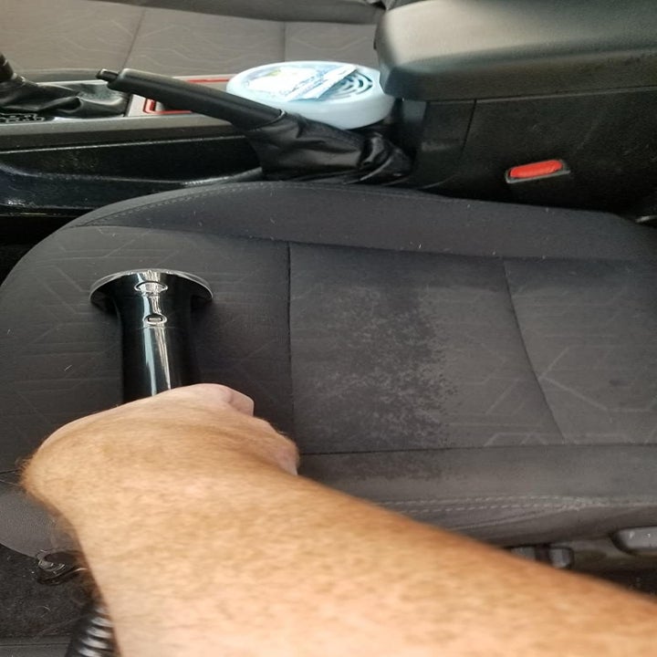 Reviewer using the brush to clean their car seat