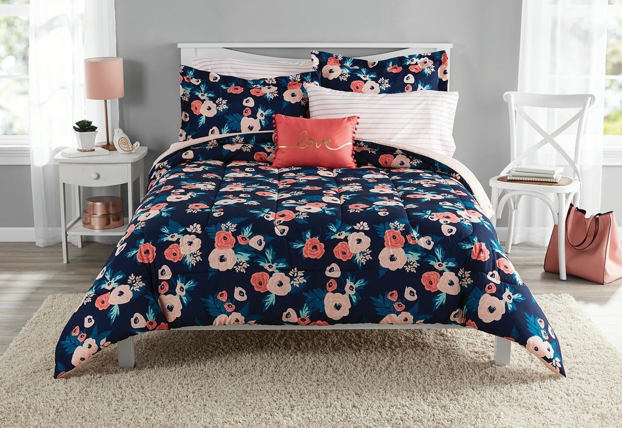 The comforter, which has coral and peach-toned flowers on a dark blue background