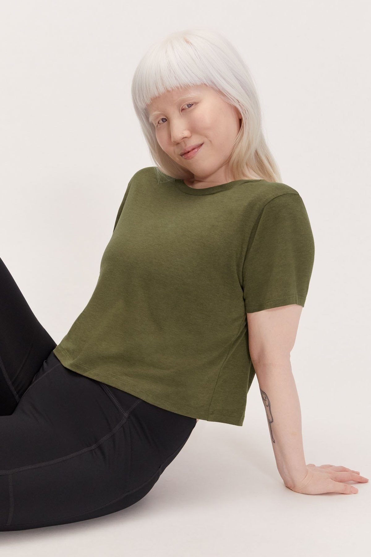 Model wears green short-sleeve crop top with black workout leggings