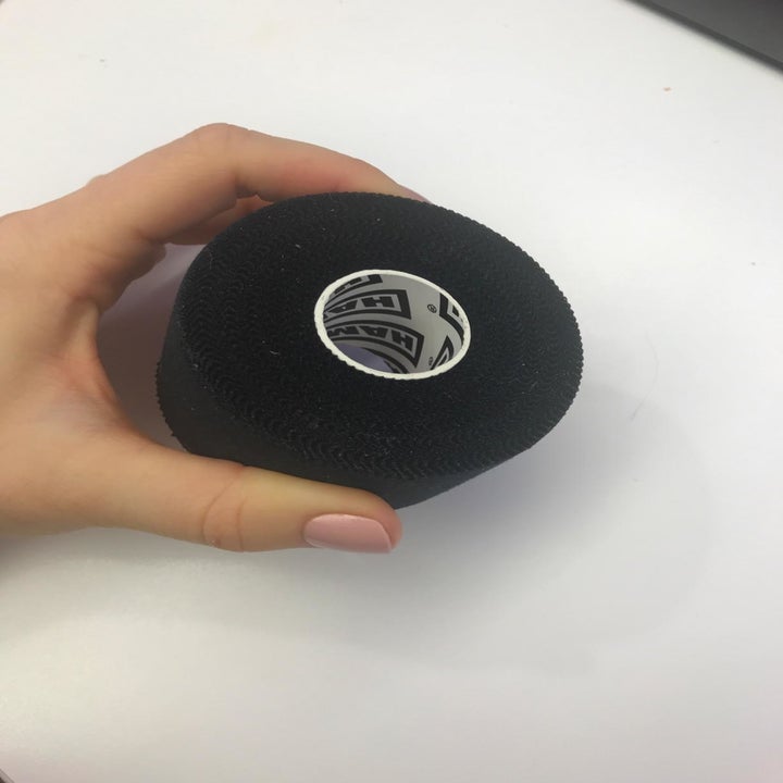 Reviewer holds roll of black athletic tape in their hand