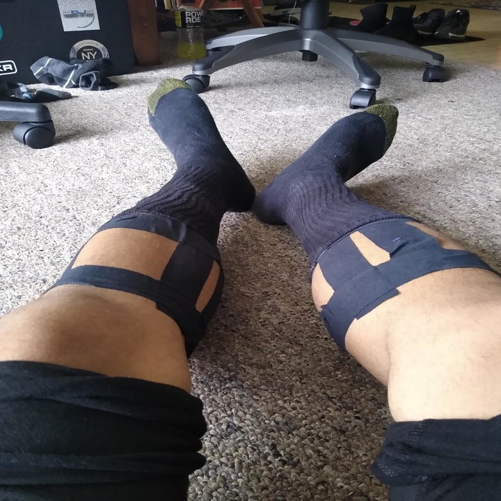 Reviewer wears black athletic tape around their calves before a workout
