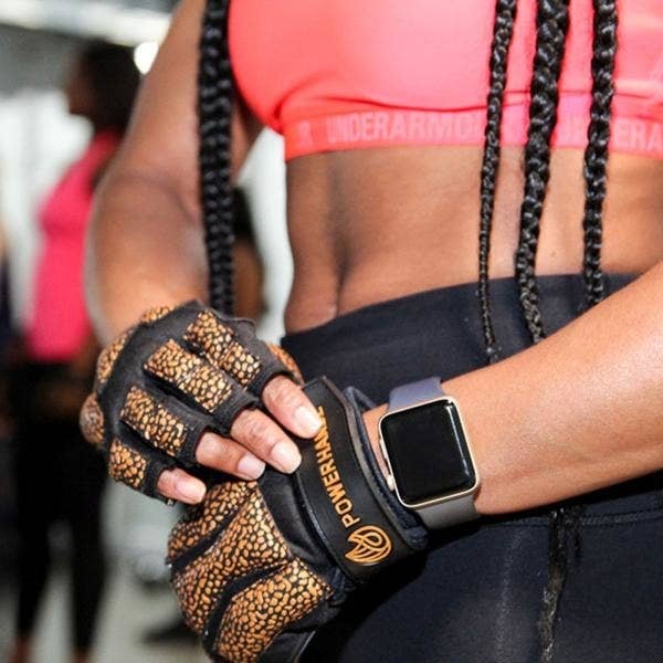 Model slips on gold and black fitness gloves on their hands