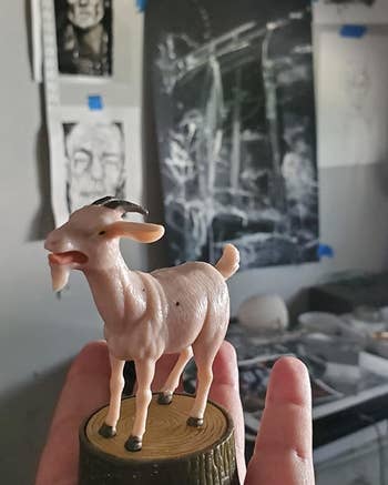 The small goat toy sitting on a reviewer's palm