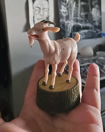 The small goat toy sitting on a reviewer's palm