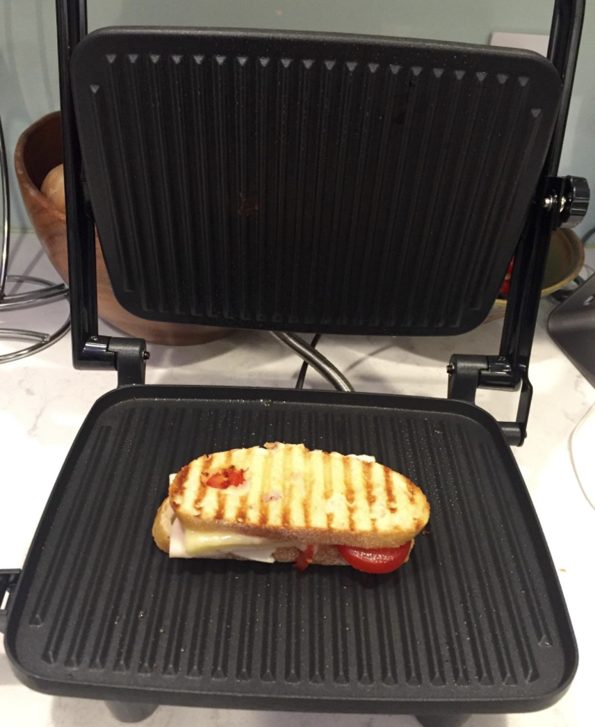 A reviewer using the panini press grill to make a sandwich