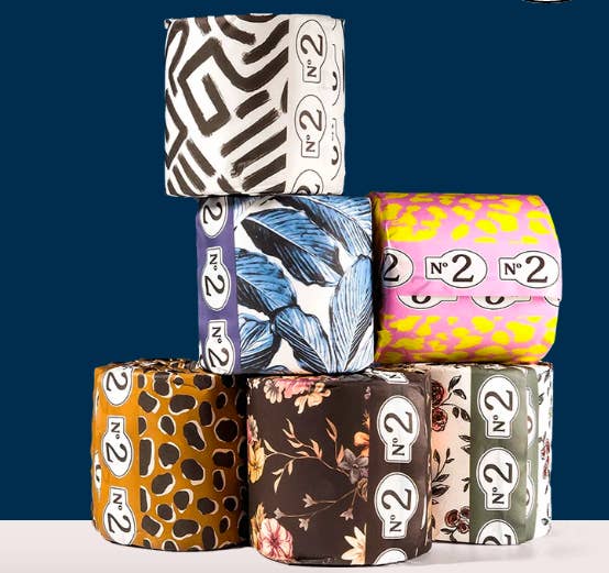 Several stacked toilet paper rolls wrapped in different bold patterns of tissue paper 