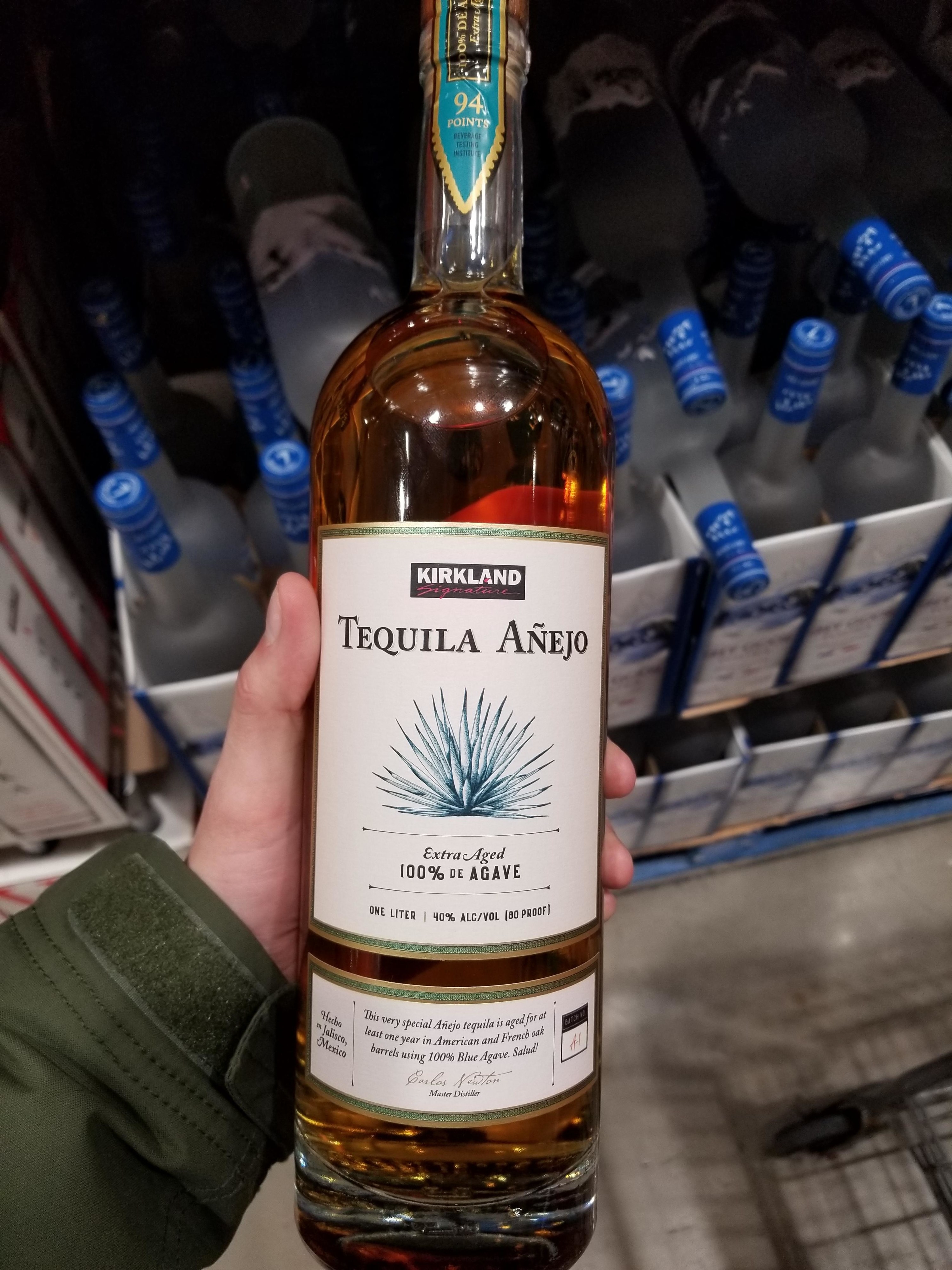 Someone holding a bottle of Kirkland tequila añejo.