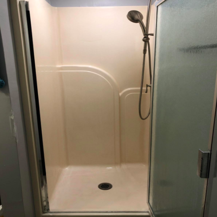 The same reviewer's shower wall no longer orange and looking clean after using the spray