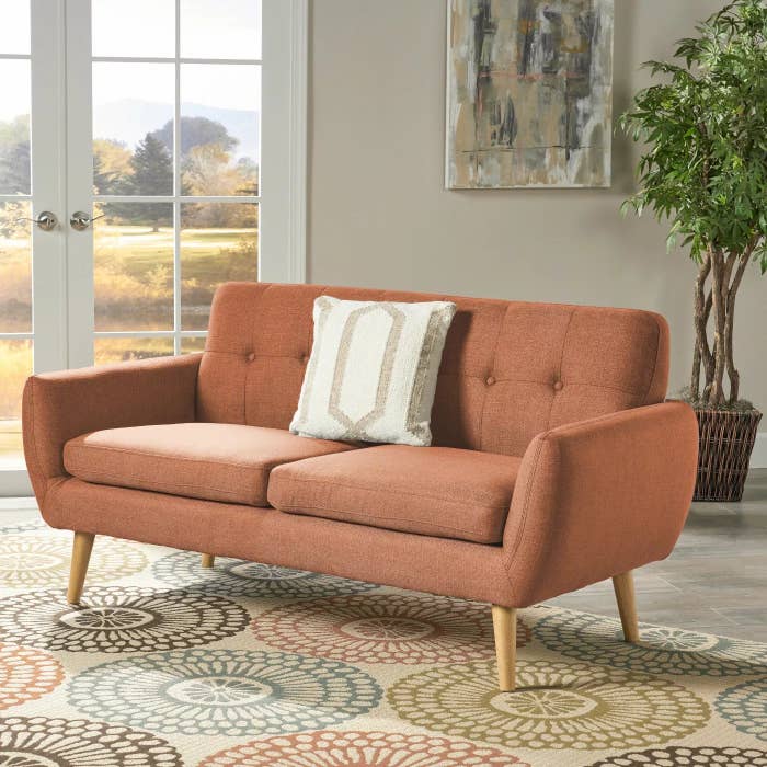 The salmon-colored couch with wooden legs