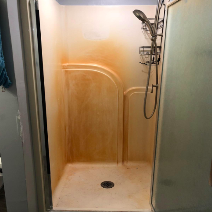 A reviewer's shower wall looking orange and rusty