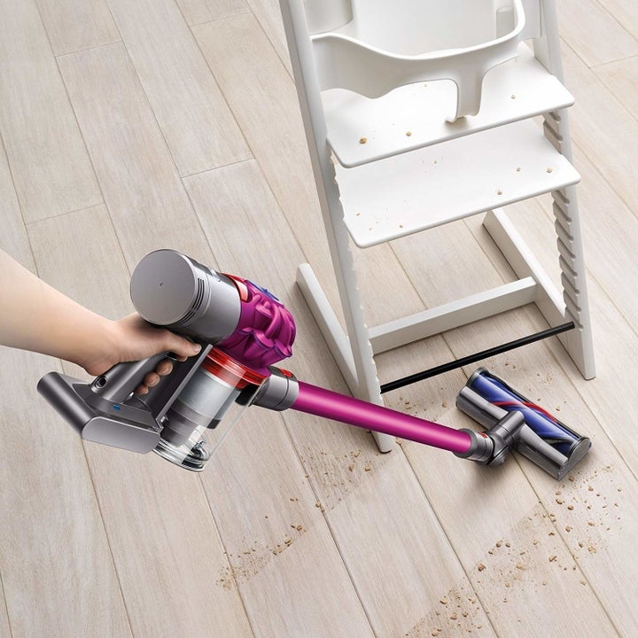 A person cleaning the floor with the cordless vacuum