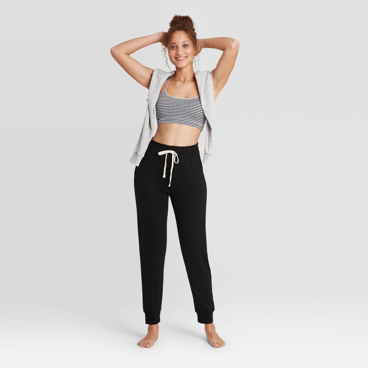 Model in black pants with sports bra and sweatshirt 
