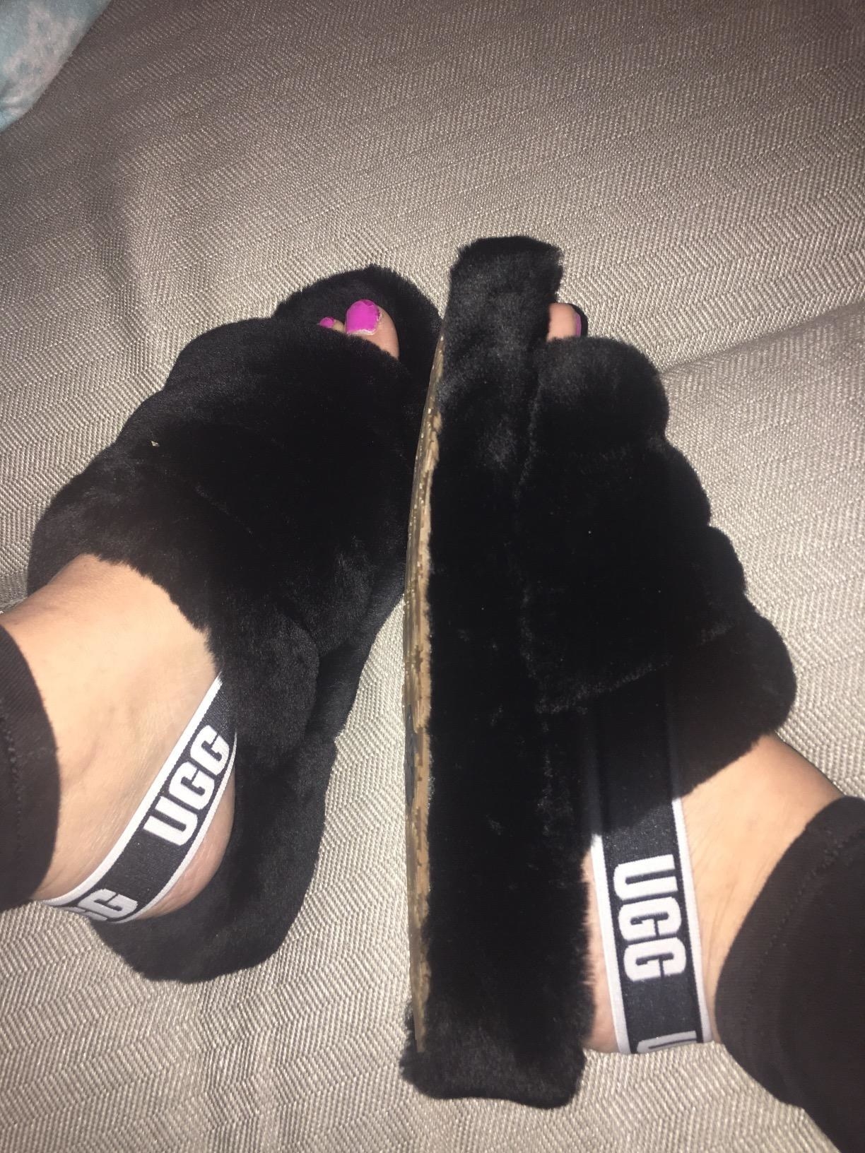 A reviewer wearing the slippers in black which are backless except for a back strap and are open-toed 