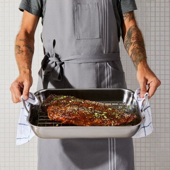 Model holding the pan with a rack of ribs on the rack