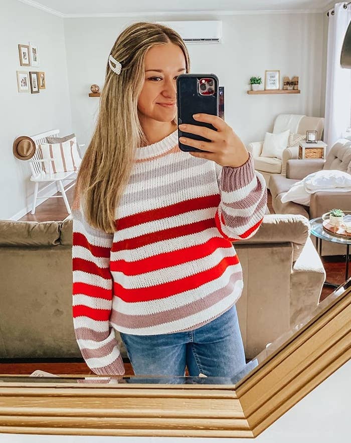 reviewer wearing a white, pink, red, and purple striped sweater 