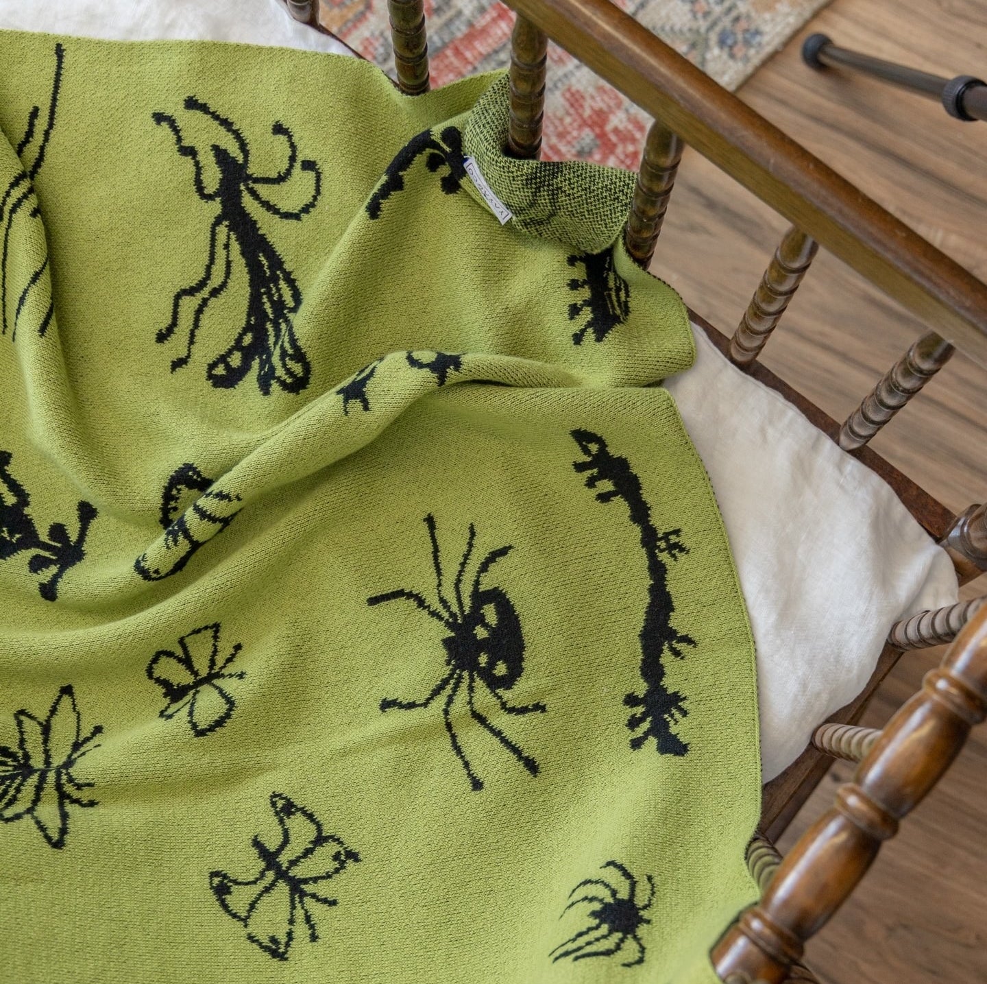 A lime green throw blanket with black bugs pattern