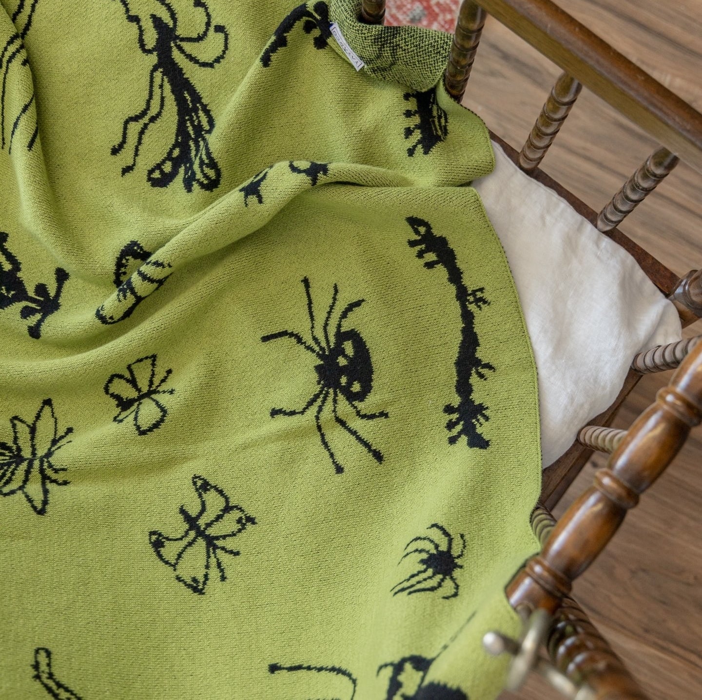 A lime green throw blanket with black bugs pattern