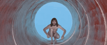 Shirtless man crawling through a tunnel