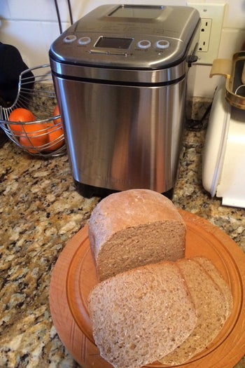 A reviewer photo of a bread machine on a counter with a plate of sliced bread 
