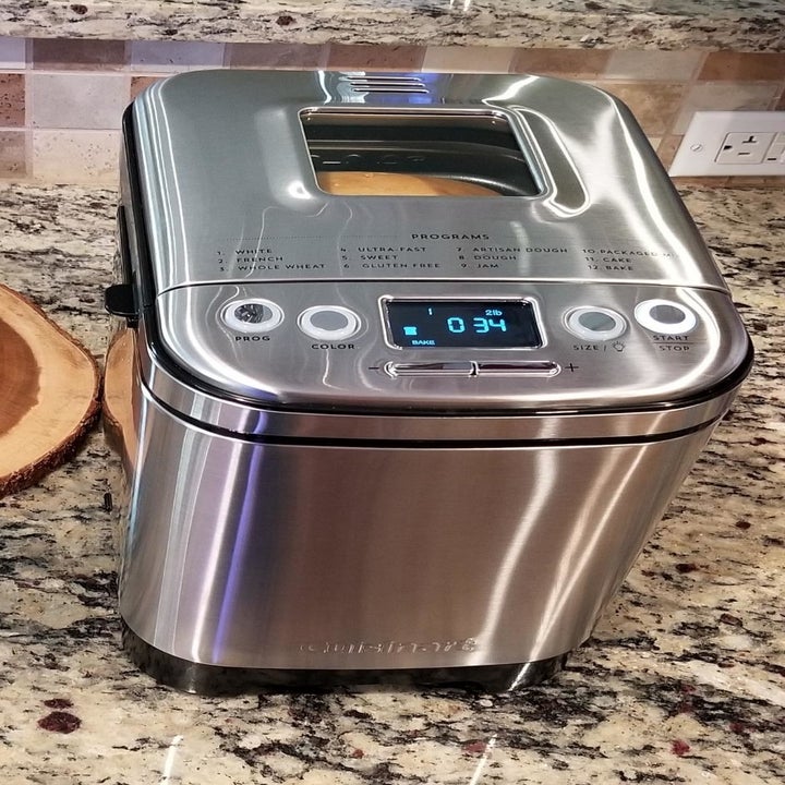 A bread maker sitting on the counter with bread visible through the clear window on the lid 