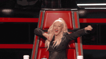 Christina Aguilera as a judge on The Voice celebrating in her seat