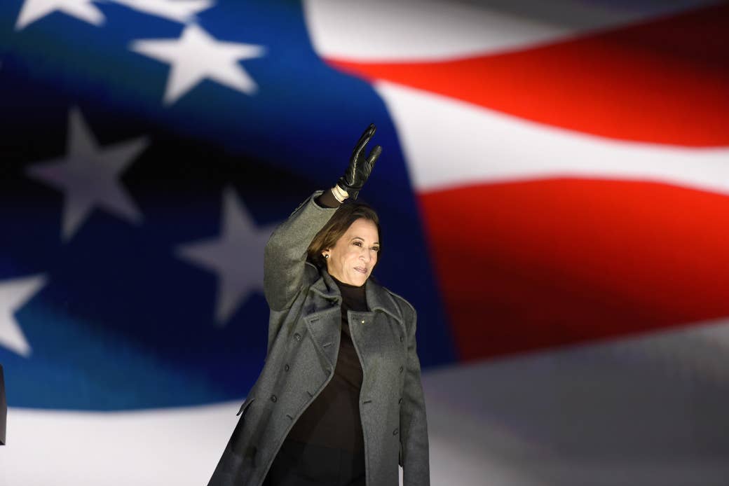 Kamala Harris waving in front of a flag.