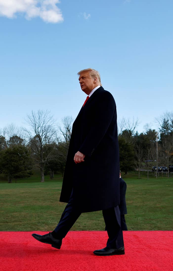 Donald Trump andando em um tapete vermelho sobre um gramado..