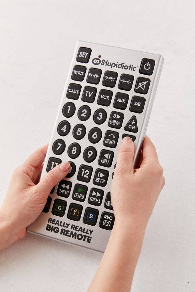 Hands holding the jumbo remote which is roughly the size of a folded newspaper