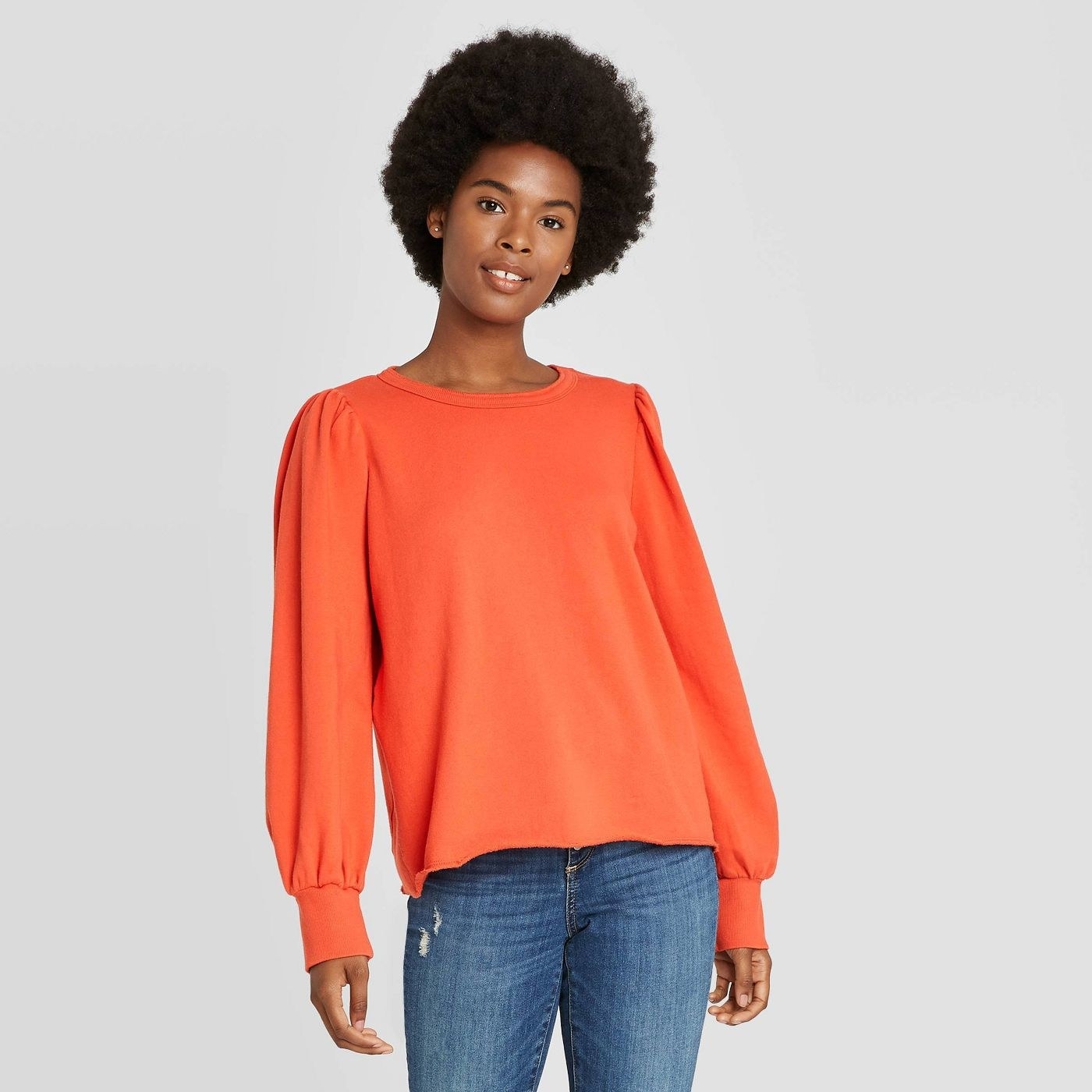 Model in orange puff sleeve sweatshirt