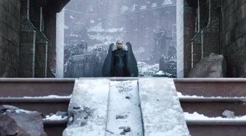 Dany caminhando ao topo dos degraus do castelo de King's Landing com o Drogon atrás dela.