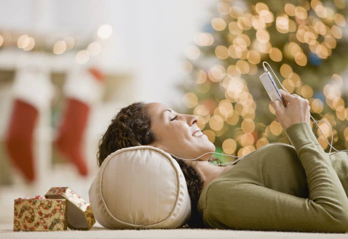 A person wearing headphones and lying on the floor with an iPod in their hands
