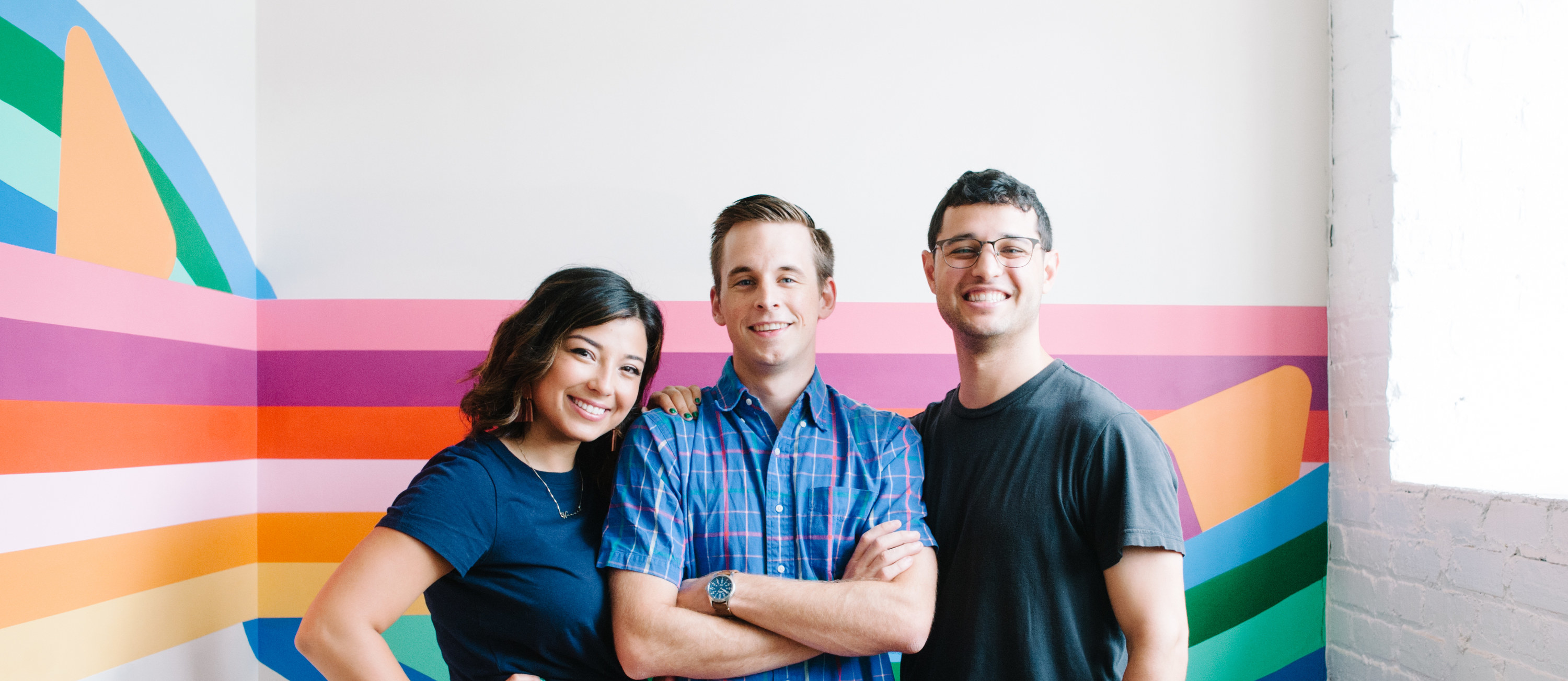 The three Nugget cofounders, Hannah Fussell, Ryan Cocca, and David Baron, standing against a colorful mural