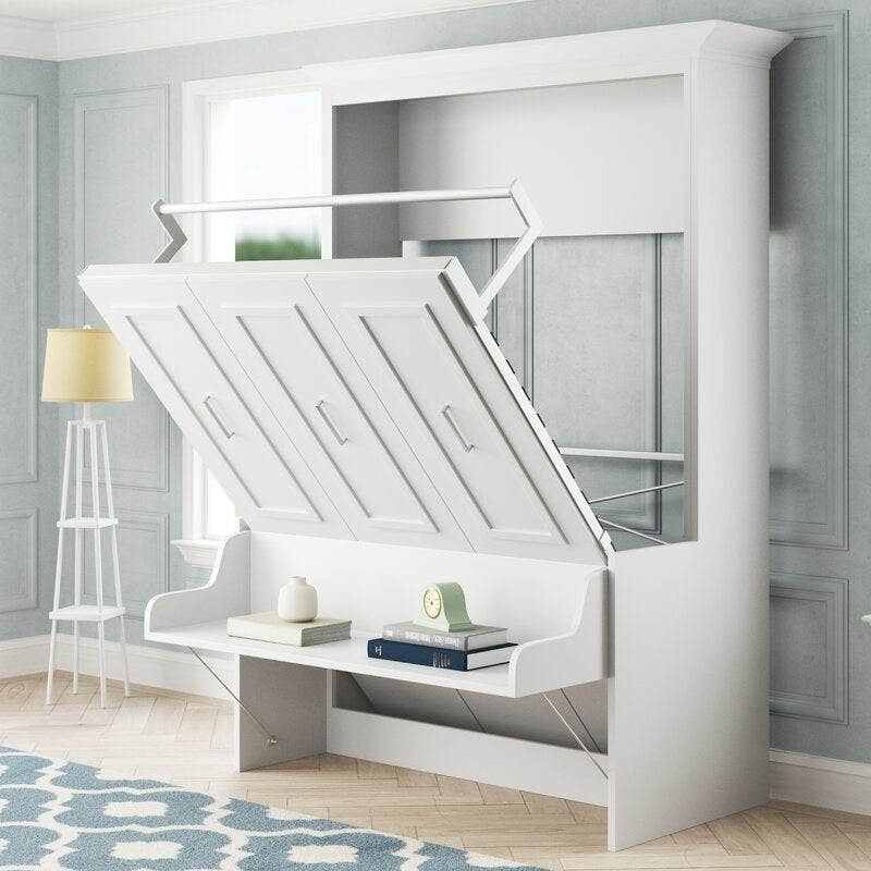 A stylish white murphy bed agape with a desk under it