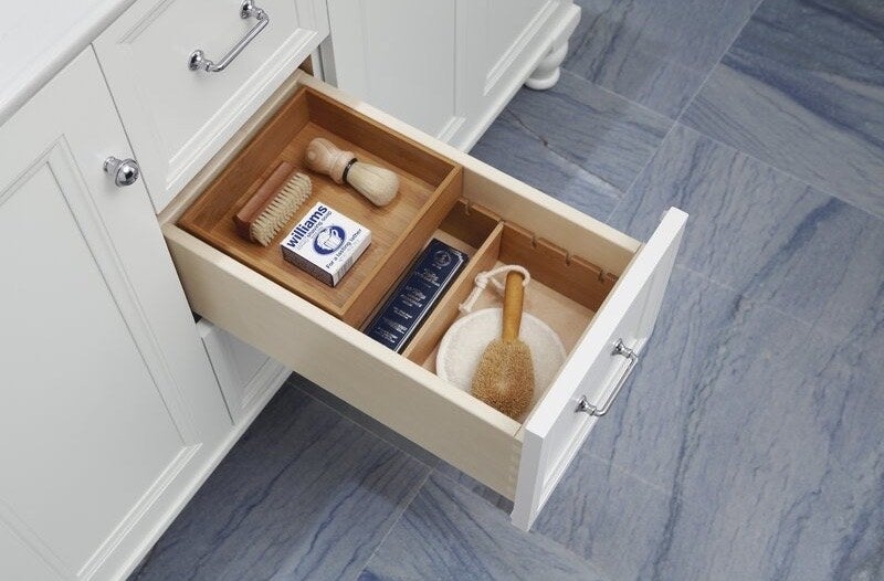 A white vanity with a drawer open and toiletries neatly organized inside
