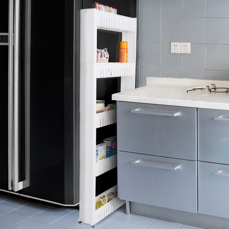 A skinny white cart wedged in between a refrigerator and kitchen counter