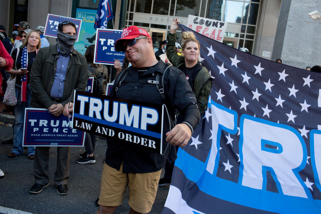 Man holding a sign that says, &quot;Trump, Law and Order&quot;