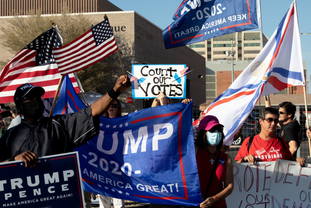 Several Trump supporters holdings signs and U.S. flags