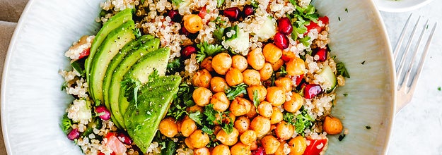 plate filled with cooked chickpeas, pomegranates, avocados, quinoa and tomatoes